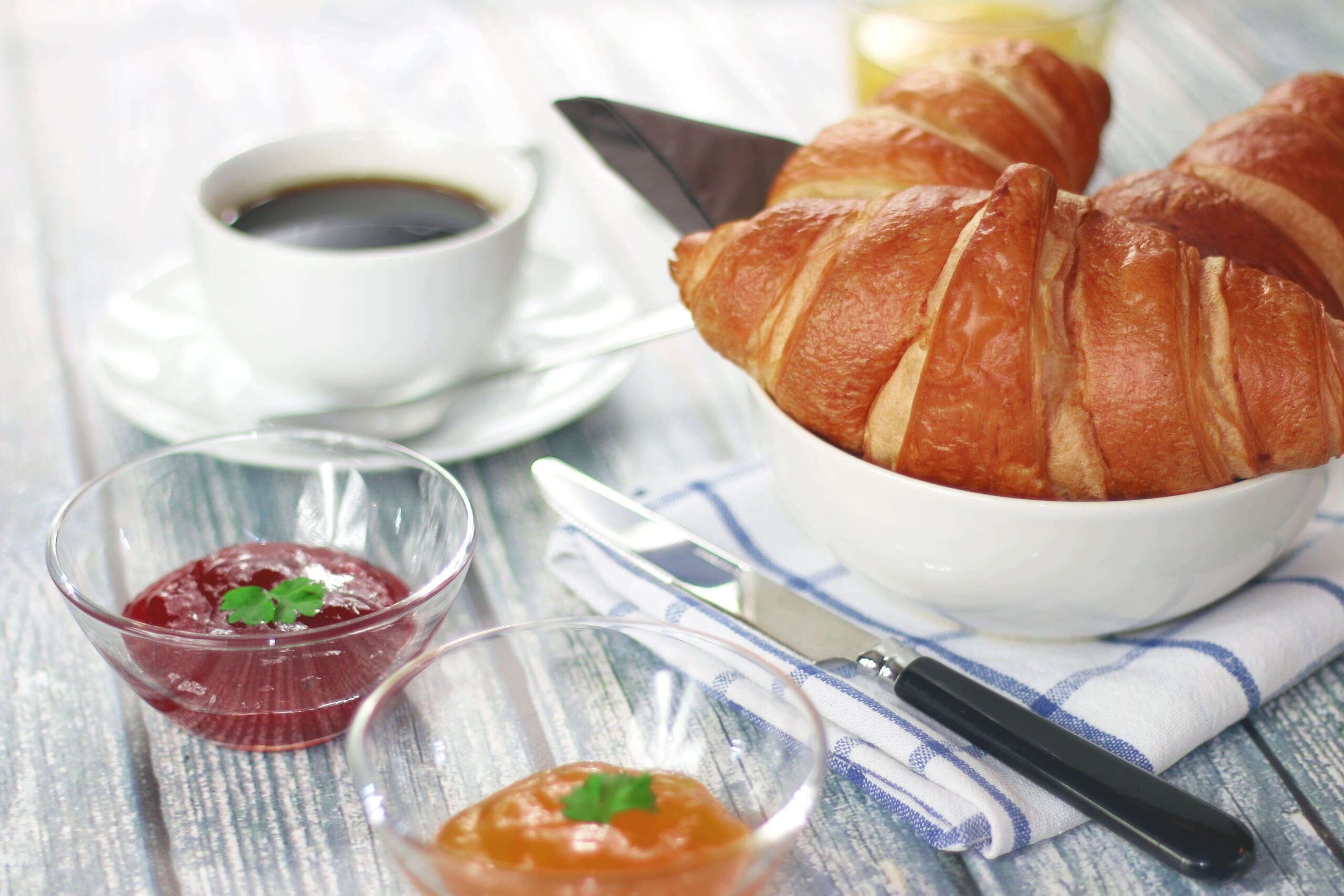 Frühstückstisch mit Kaffee, Croissant und Marmelade, wie er beim Arbeitsfrühstück aussehen könnte